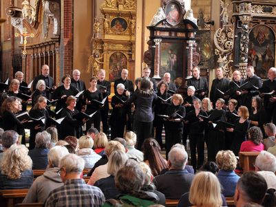 Der Südwestdeutsche Kammerchor in schwarzer Konzertkleidung singt vor zahlreichem Publikum in der Kathedrale von Frombork in Polen. Die Kirche ist mit barocken Altären und Gemälden prunkvoll ausgestattet.